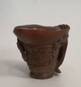 An antique Chinese carved libation cup. Decorated with figures and foliage with a two strand handle.