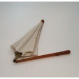 An Oriental antique folding cream silk parasol with an amber resin tapering handle carved with