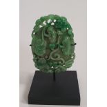 A Chinese pierced jade carving, decorated with pea pods on a bi disc for immortality, lucky bats and