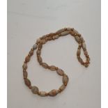 An ancient graduated agate, mother of pearl and alabaster bead necklace with gilt metal knot