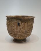 An Islamic Kashan cream glazed ceramic footed vessel with a relief calligraphy design and flared