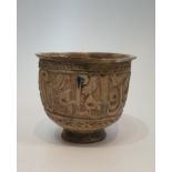 An Islamic Kashan cream glazed ceramic footed vessel with a relief calligraphy design and flared