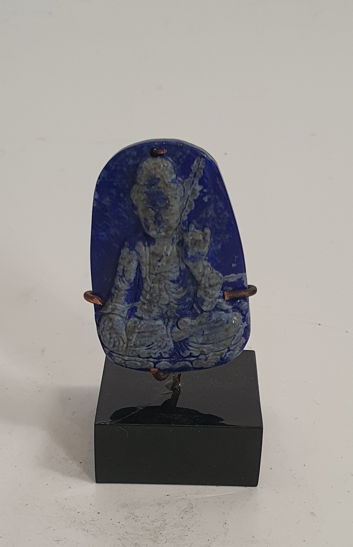 A Chinese Lapis Lazuli pendant carved with a Buddha. Mounted on a metal display stand. H.5.5cm