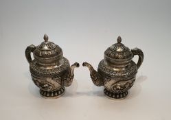 A pair of Chinese Tibetan white metal repousse design wine jugs. Decorated with animals, symbols and