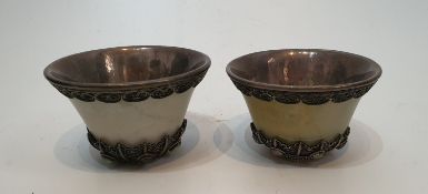 A pair of Chinese carved jade and white metal lined cups with white metal filigree wire work inset