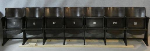 A row of seven vintage theatre seats with laminated plywood backs and seats and painted seat