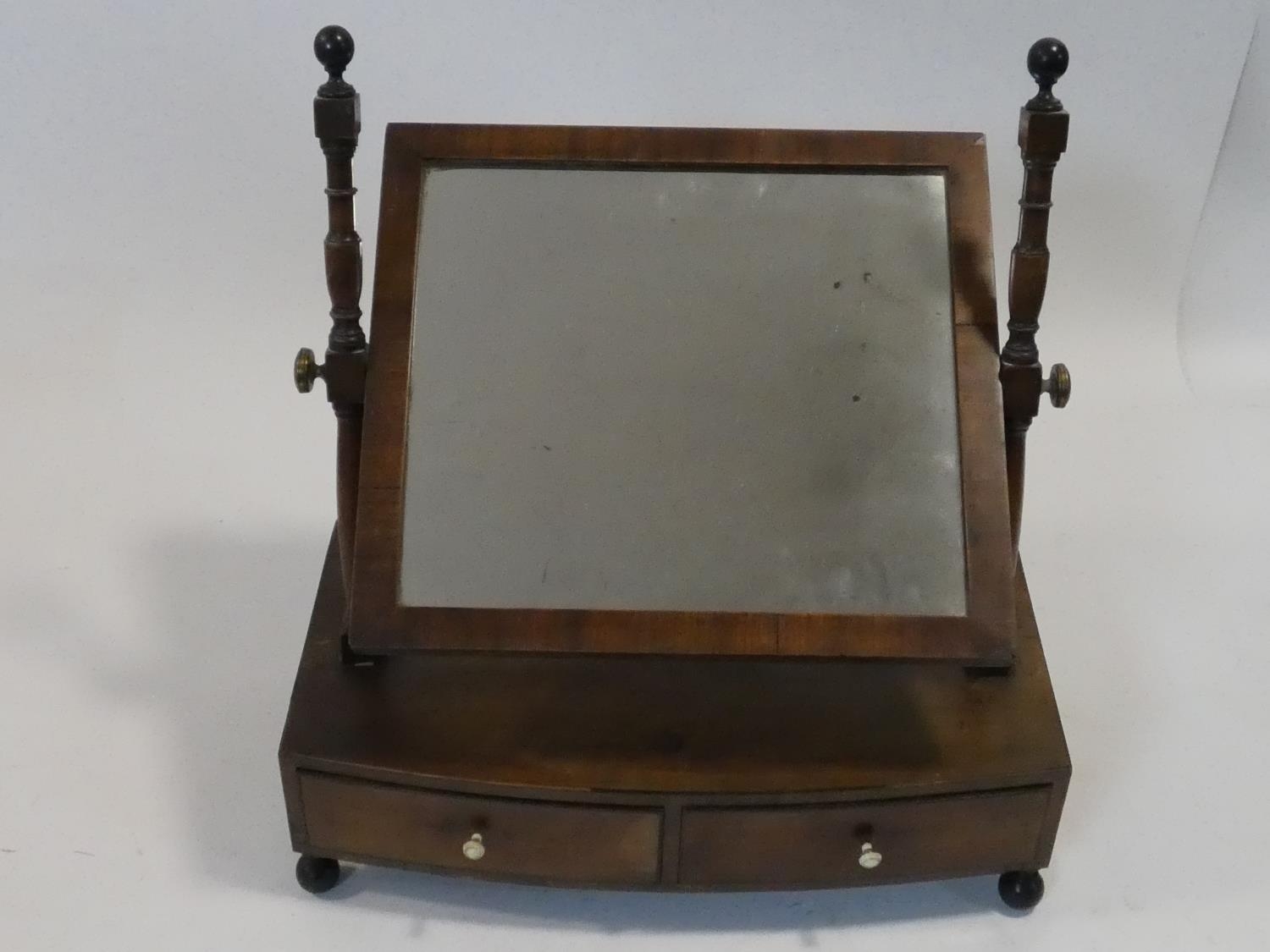 A Georgian mahogany swing toilet mirror fitted with original plate on bowfronted base with two