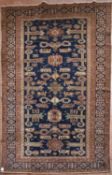 A Kazak rug with repeating stylised design across a midnight field within multiple borders. L.