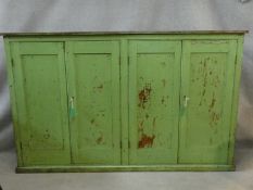 A 19th century painted pantry cupboard with two pairs of panel doors enclosing shelves on plinth