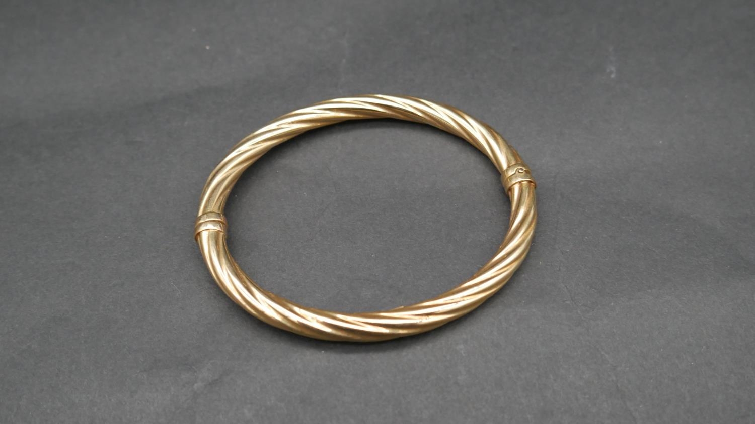 A vintage 9 ct yellow gold hollow twist bangle with secure loop clasp. Italian hallmarks, stamped