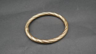 A vintage 9 ct yellow gold hollow twist bangle with secure loop clasp. Italian hallmarks, stamped