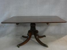 A Regency mahogany tilt top dining table on reeded swept quadruped supports terminating in brass cap