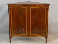 An Edwardian figured mahogany and satinwood inlaid serpentine fronted corner cabinet on square