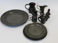 A collection of antique pewter items. Including plates, measures, pepper shaker, jug and tankards.