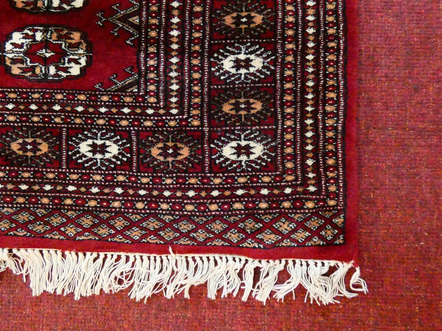 A Bokhara style rug with repeating gul motifs across the madder field enclosed by mutliple geometric - Image 3 of 7
