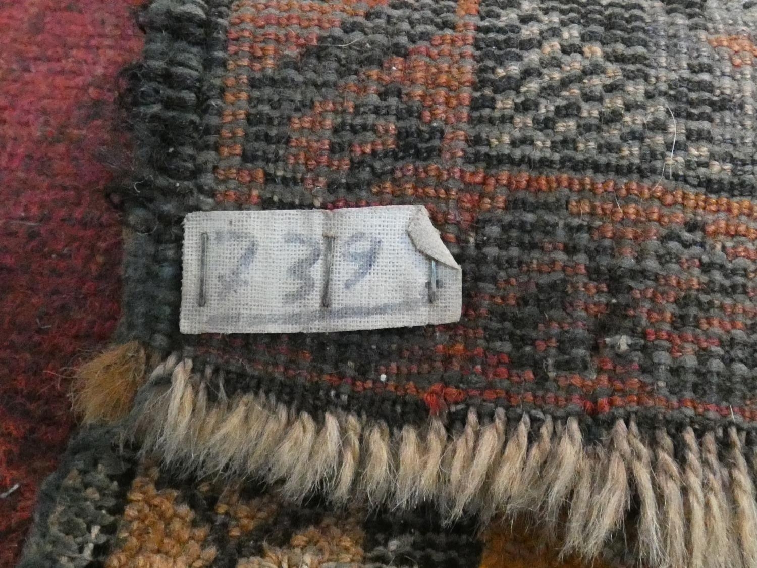 An Eastern rug with repeating gul motifs across the madder field within highly stylised foliate - Image 5 of 5