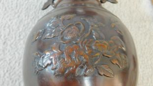 A Chinese bronze vase with floral decoration and twin dragon handles on carved and pierced