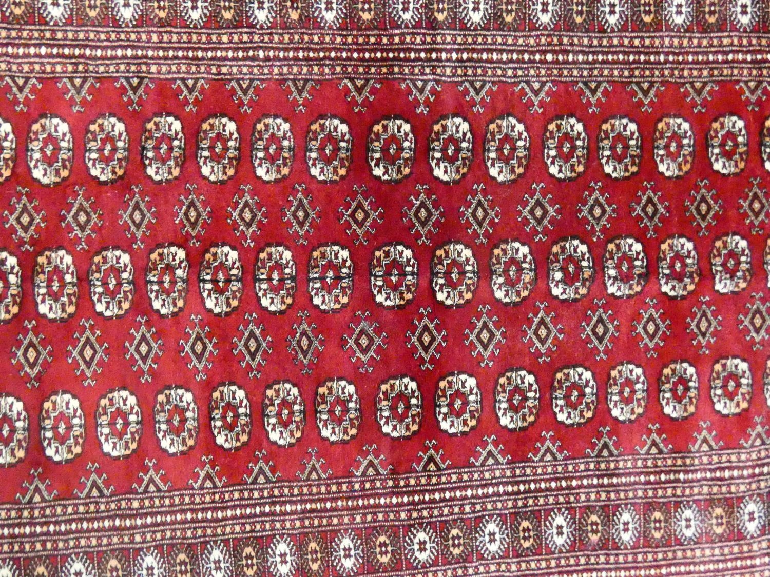 A Bokhara style rug with repeating gul motifs across the madder field enclosed by mutliple geometric - Image 2 of 7