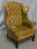 A Georgian style wingback armchair in buttoned leather upholstery. H.116cm