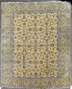 A Persian Kashan carpet with palmettes and scrolling foliate design on a biscuit ground contained by