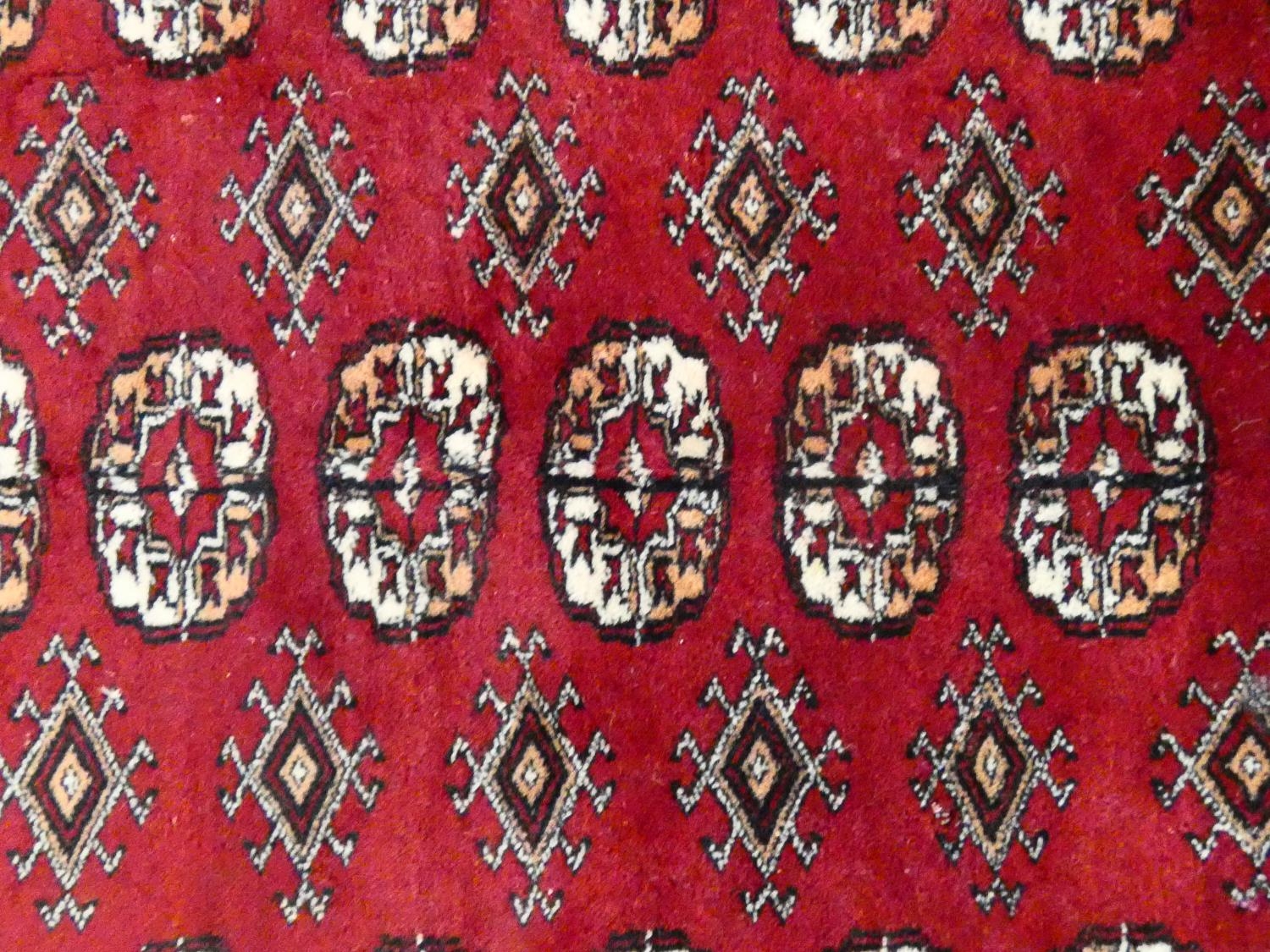 A Bokhara style rug with repeating gul motifs across the madder field enclosed by mutliple geometric - Image 5 of 7