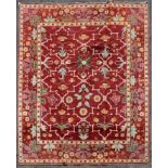 A Moughal design carpet with repeating stylised floral pattern across a madder ground within foliate