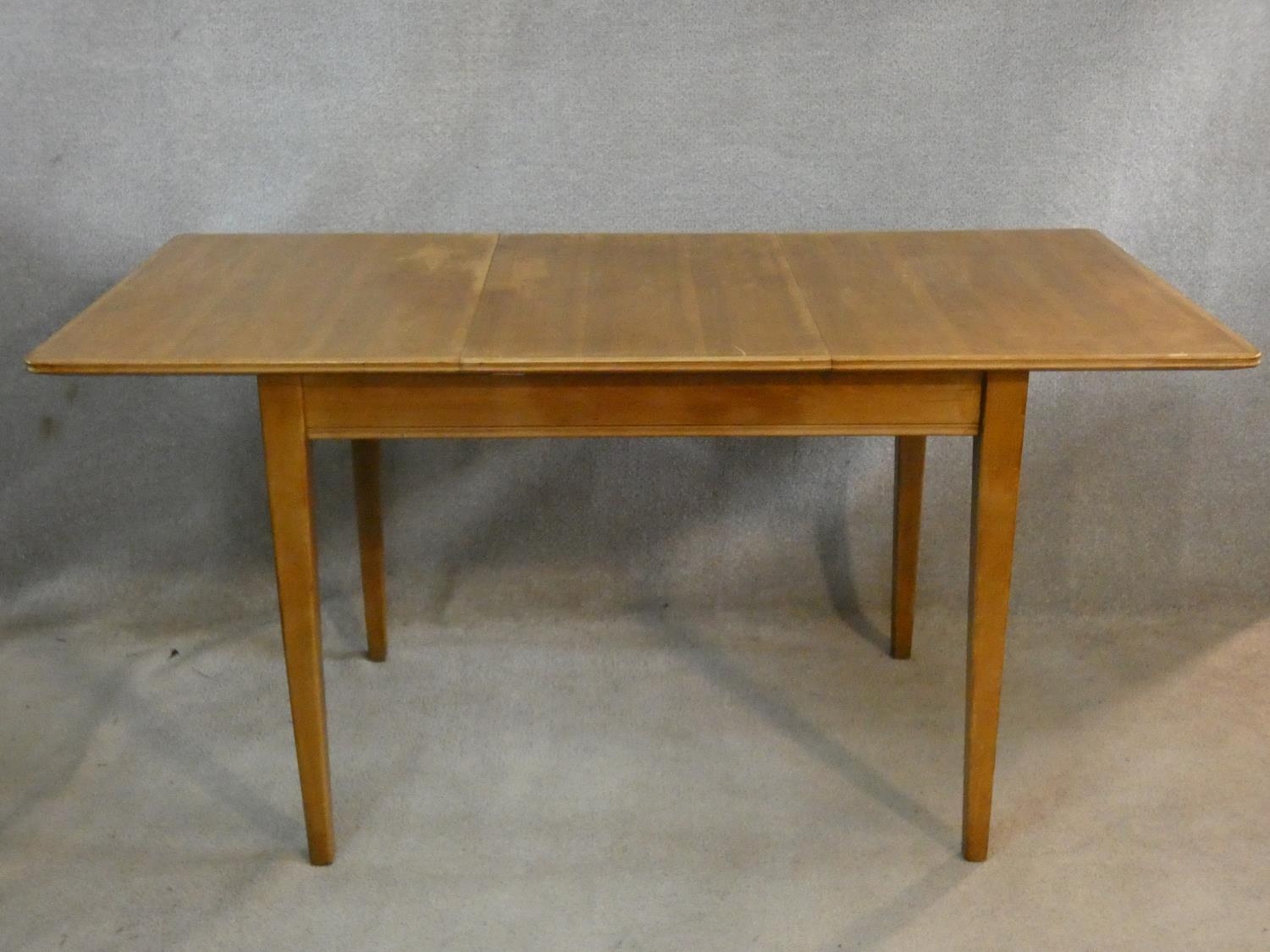 A mid century vintage teak dining table with extra leaf on square tapering supports. H.76 L.154 W.