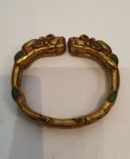 A Tibetan gilded bronze two headed dragon bangle inset with turquoise and red stone cabochons for