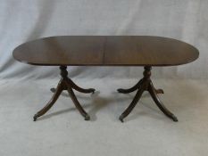 A Regency style mahogany and satinwood strung twin pillar dining table on swept quadruped supports
