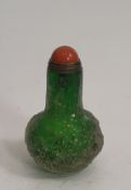 A green Peking glass carved snuff bottle, decorated with flowers and clouds with dyed orange agate
