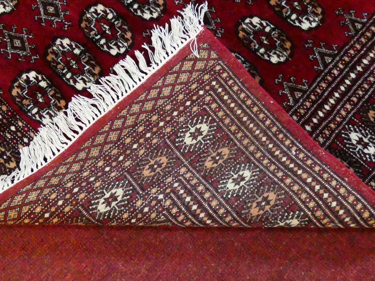 A Bokhara style rug with repeating gul motifs across the madder field enclosed by mutliple geometric - Image 4 of 7