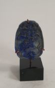 A Chinese carved lapis lazuli pendant with a lucky bat, coins and fungi. Mounted on a metal