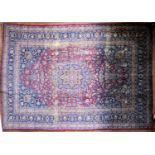 A Persian Mashad carpet with double central floral medallions on madder field within sapphire floral