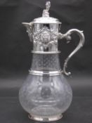 A silver plated and cut glass claret jug with repousse detailing. The glass jug has an engraved star