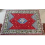 A Persian carpet with central lozenge medallion on madder ground with stylised motifs across the