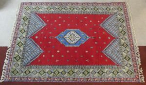 A Persian carpet with central lozenge medallion on madder ground with stylised motifs across the