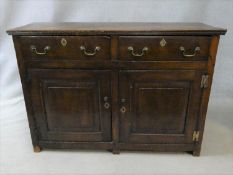 A Georgian country oak side cabinet with two frieze drawers above fielded panel doors with