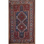 An antique Kazak rug with double lozenge medallion on indigo ground within a madder field