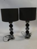A pair of contemporary bobbin design table lamps with black shades. H.63cm