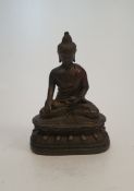 An antique Tibetan bronze buddha figure sitting on a lotus flower. H.10cm