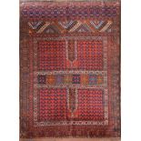An Afghan rug with geometric design across the madder field within stylised floral borders. L.
