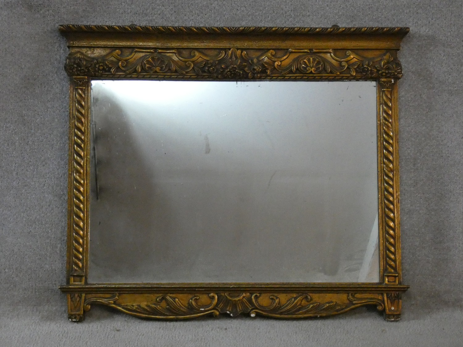 A 19th century gilt and gesso framed overmantel mirror with original plate flanked by spiral twist