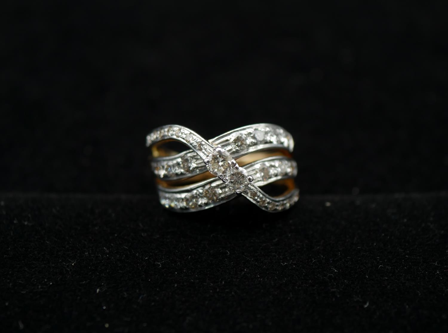 An 18 carat yellow and white gold and diamond two stone cross over ring, set with a combined