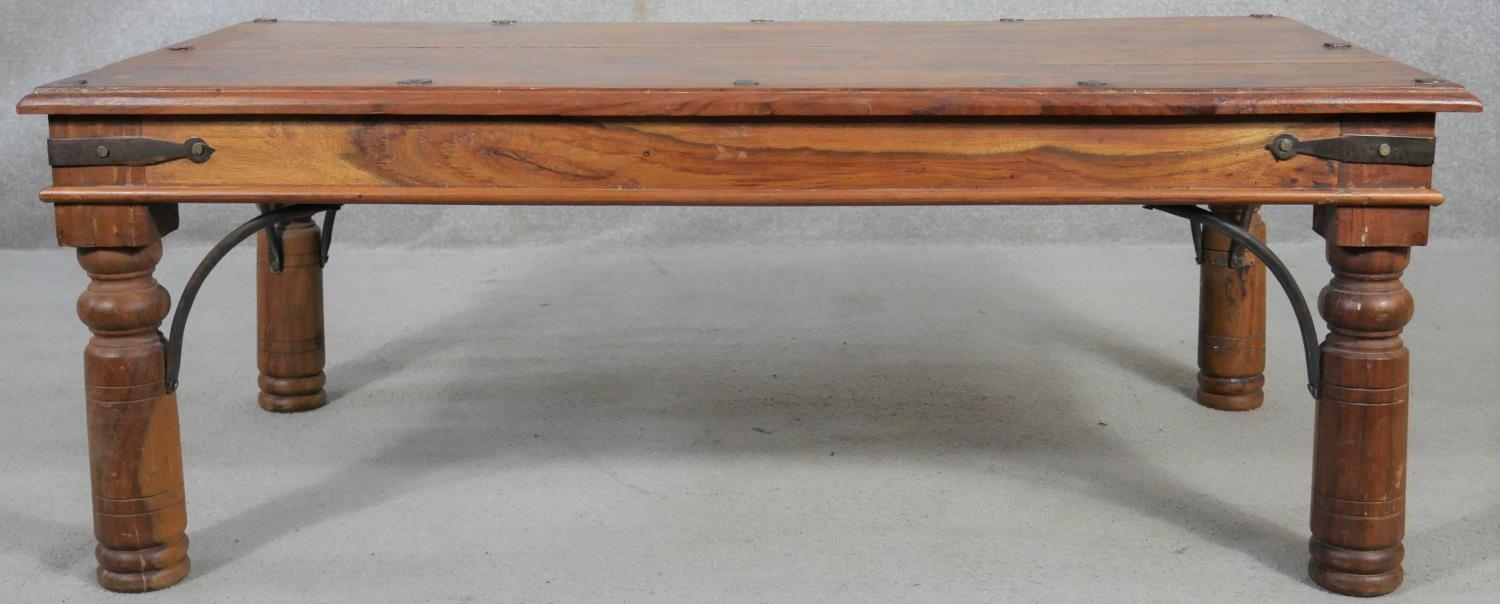 An Indian teak and metal bound coffee table on circular section supports. H.41 L.110 D.60cm