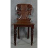 A Regency mahogany hall chair with scroll carved back above panel seat on reeded tapering