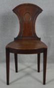 A late Georgian mahogany hall chair with shield shaped back above panel seat on square tapering