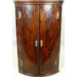 A Georgian flame mahogany bow fronted corner cabinet with original brass work. H.108 W.68 D.46cm