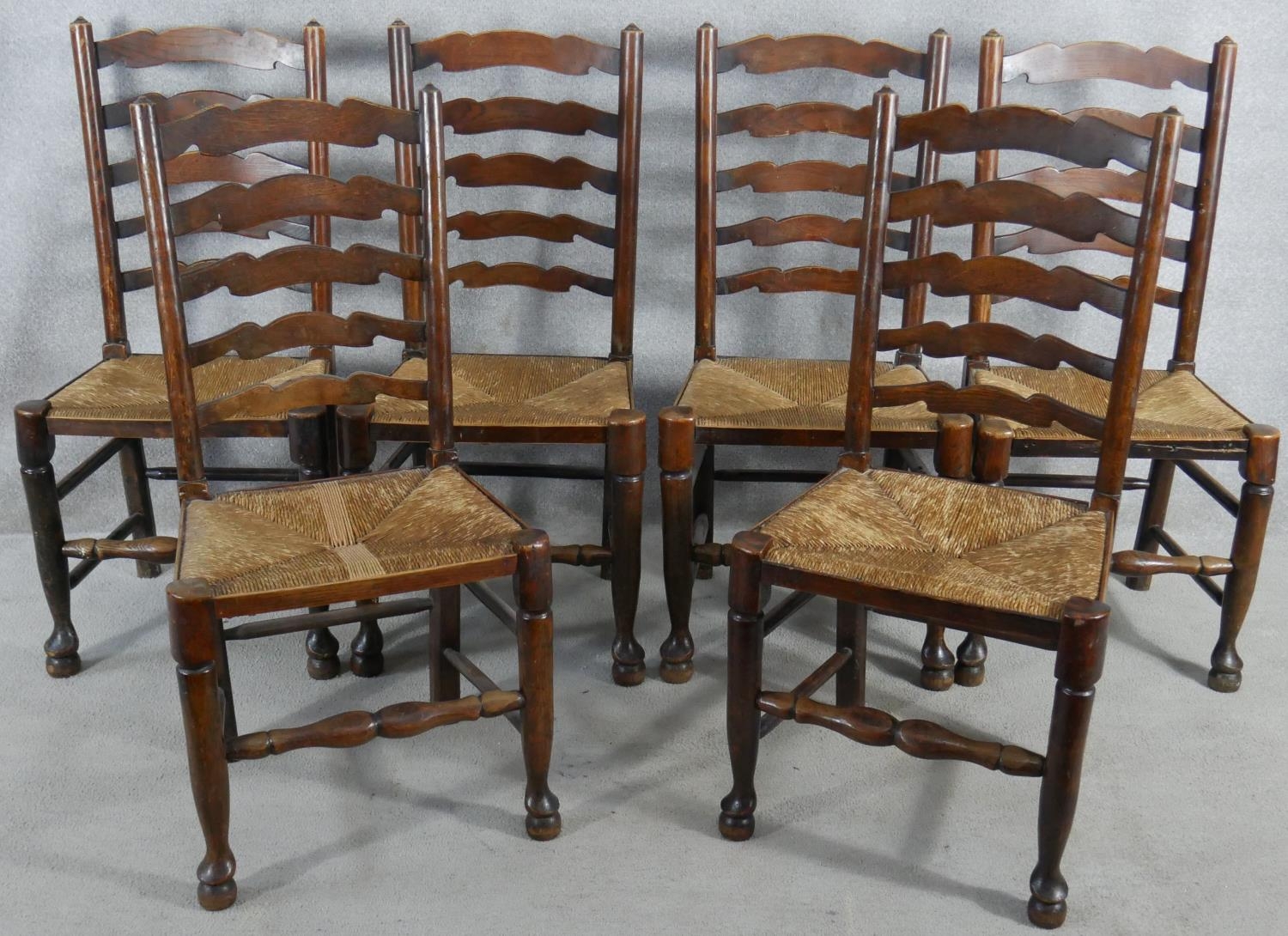 A set of six oak Lancashire ladderback dining chairs with woven rush seats on turned stretchered