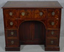 A Georgian flame mahogany and satinwood strung kneehole desk with twin brass carrying handles and an