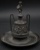 An antique bronze inkwell in the form of a two handled Grecian urn with a human form finial and